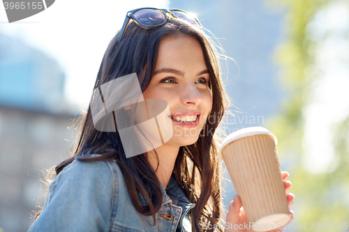 Image of happy young woman drinking coffee on city street