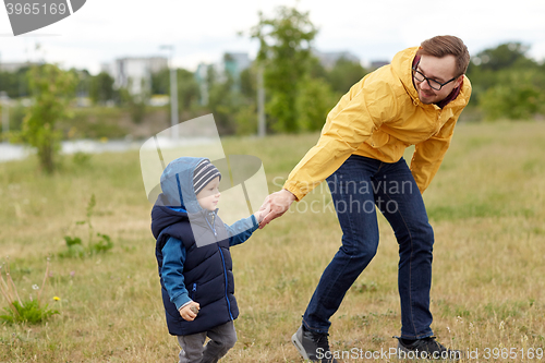 Image of happy father and little son walking outdoors