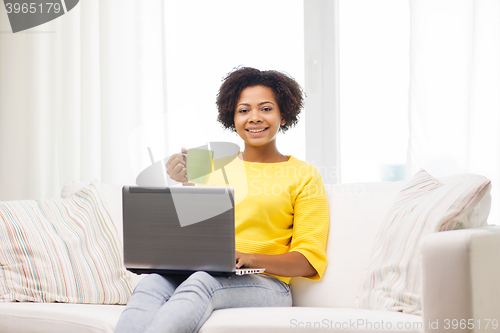 Image of happy african american woman with laptop at home