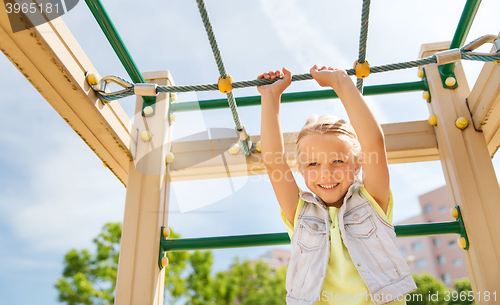 Image of happy little girl climbing on children playground