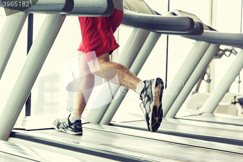 Image of close up of male legs running on treadmill in gym