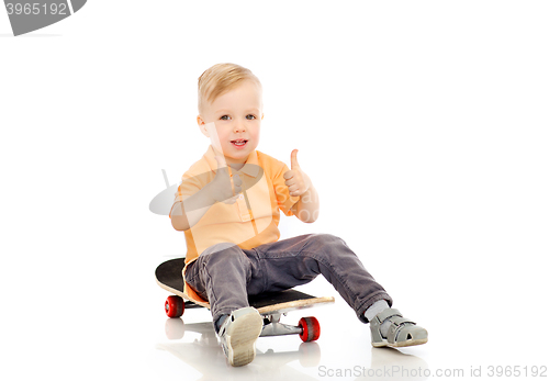 Image of happy little boy on skateboard showing thumbs up