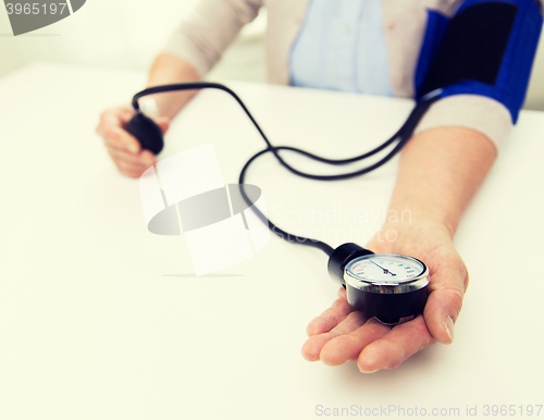 Image of old woman with tonometer checking blood pressure