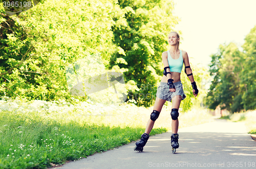 Image of happy young woman in rollerblades riding outdoors