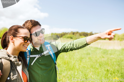 Image of happy couple with backpacks hiking outdoors