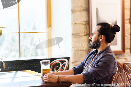 Image of happy man drinking beer at bar or pub