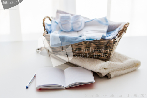 Image of close up of baby clothes for newborn and notebook