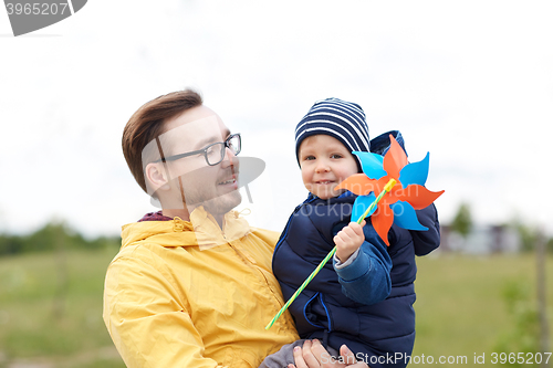 Image of happy father and son with pinwheel toy outdoors