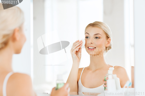 Image of young woman with lotion washing face at bathroom