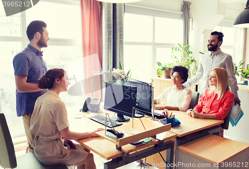 Image of happy creative team talking in office