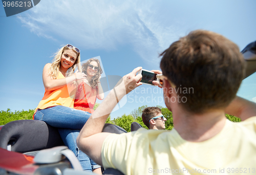 Image of friends driving in car and photographing