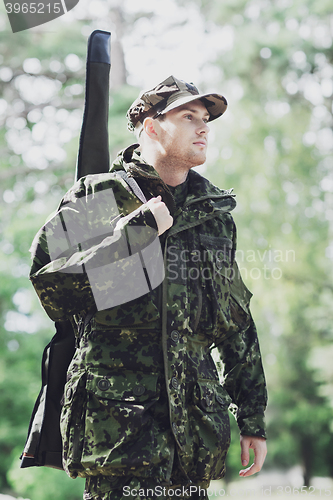 Image of young soldier or hunter with gun in forest