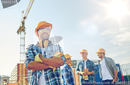 Image of group of smiling builders in hardhats outdoors