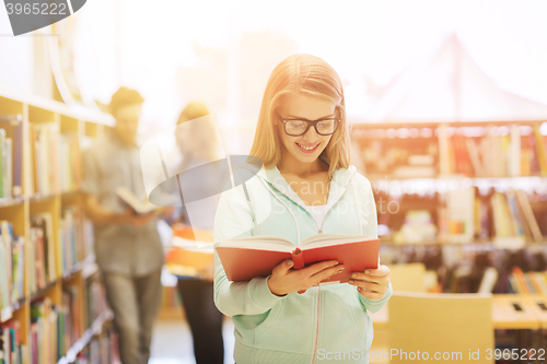 Image of happy student girl or woman with book in library