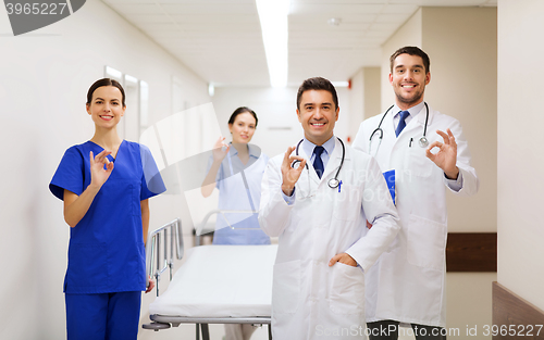 Image of happy doctors with gurney showing ok at hospital