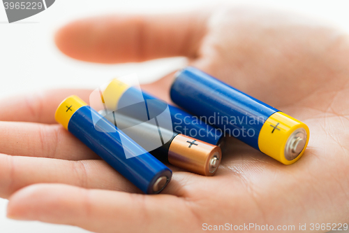 Image of close up of hands holding alkaline batteries heap