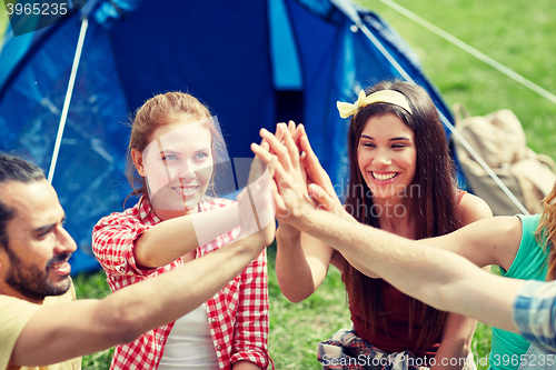 Image of happy friends making high five at camping