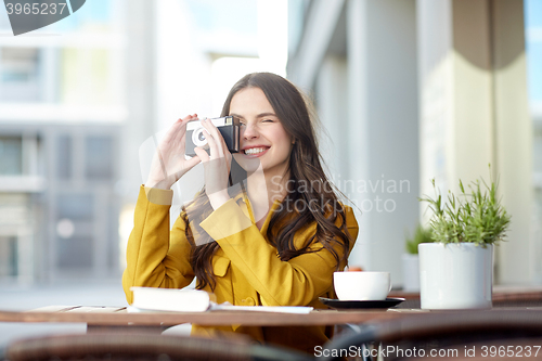 Image of happy tourist woman with camera at city cafe