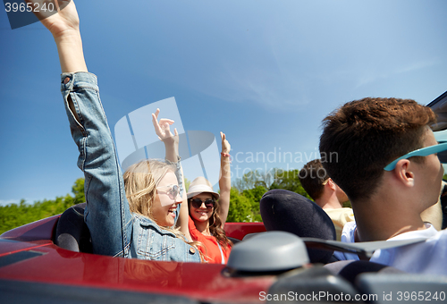 Image of happy friends driving in cabriolet car at country