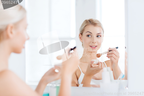 Image of woman with makeup brush and powder at bathroom