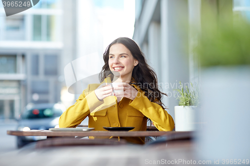 Image of happy woman drinking cocoa at city street cafe
