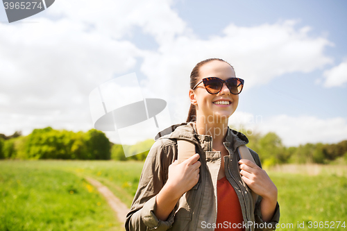 Image of happy young woman with backpack hiking outdoors