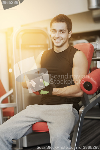 Image of smiling young man with tablet pc computer in gym