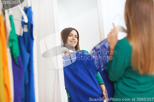 Image of happy woman choosing clothes at home wardrobe