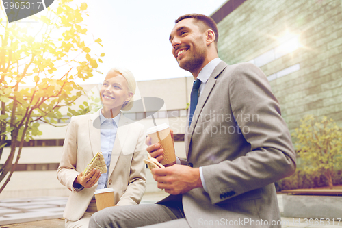 Image of smiling businessmen with paper cups outdoors
