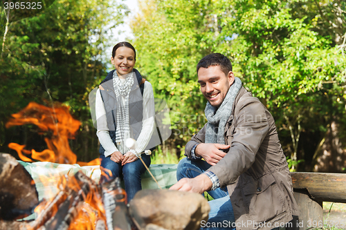 Image of happy couple roasting marshmallow over camp fire