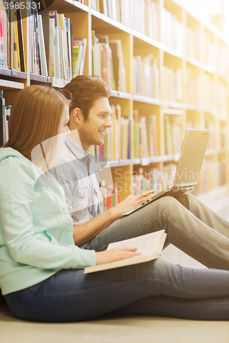 Image of happy students with laptop in library