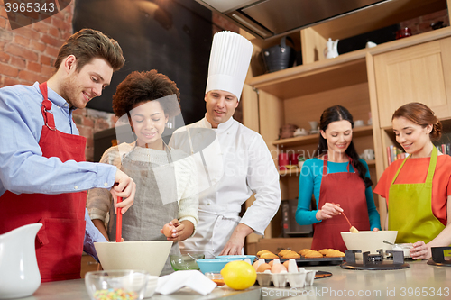 Image of happy friends and chef cook baking in kitchen