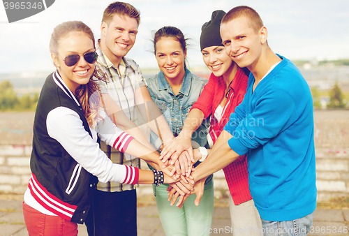 Image of teenagers hands on top of each other outdoors