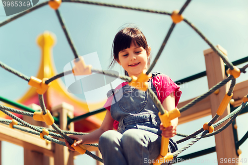 Image of happy little girl climbing on children playground