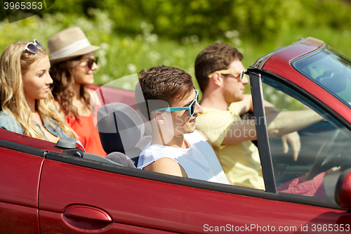 Image of happy friends driving in cabriolet car