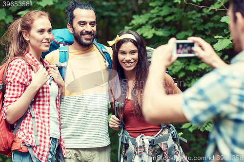 Image of friends with backpack photographing by smartphone