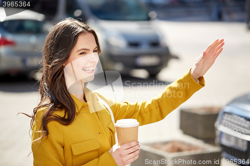 Image of happy young woman drinking coffee on city street