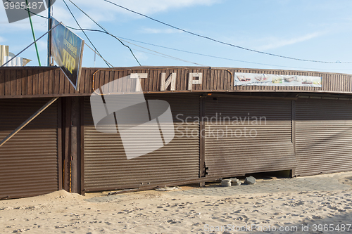 Image of Vityazevo, Russia - March 7, 2016: meadow covered pavilion with a broken roller shutters and the signboard \"Tir\", sanded in the offseason