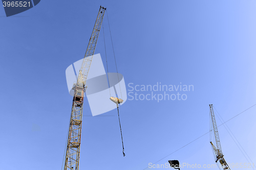 Image of Crane and building construction site against blue sky