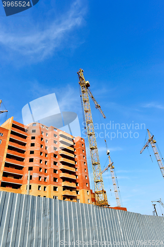 Image of Crane and building construction site against blue sky