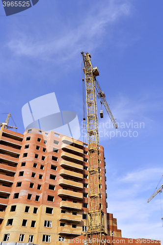 Image of Crane and building construction site against blue sky