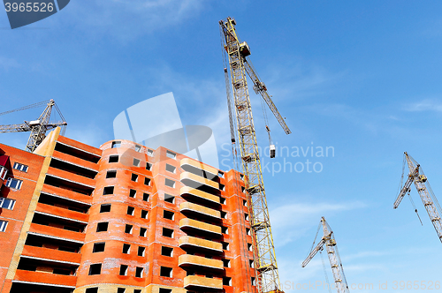Image of Crane and building construction site against blue sky