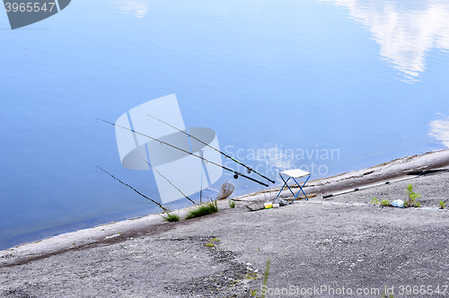 Image of Chair with fishing poles and fishing equipment at the lake