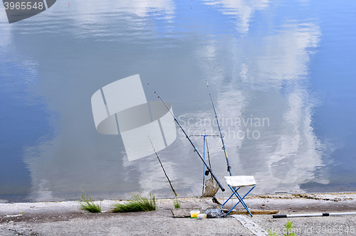 Image of Chair with fishing poles and fishing equipment at the lake