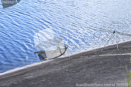 Image of Chair with fishing poles and fishing equipment at the lake