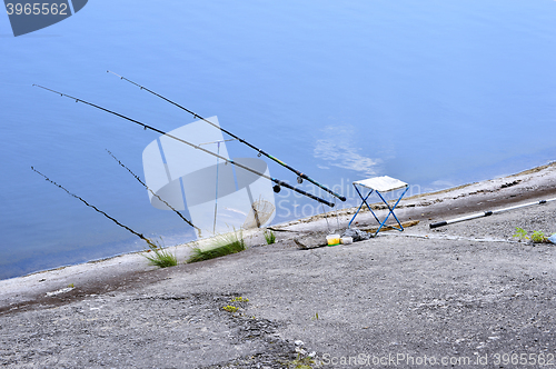 Image of Chair with fishing poles and fishing equipment at the lake