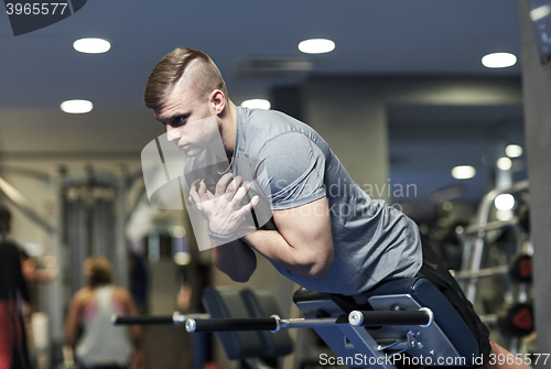 Image of young man flexing back muscles on bench in gym