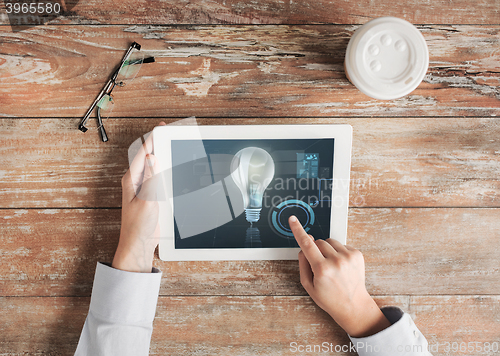 Image of close up of hands with tablet pc and lighting bulb