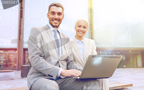 Image of smiling businesspeople with laptop outdoors