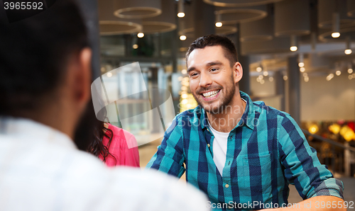 Image of happy man meeting with friends at restaurant